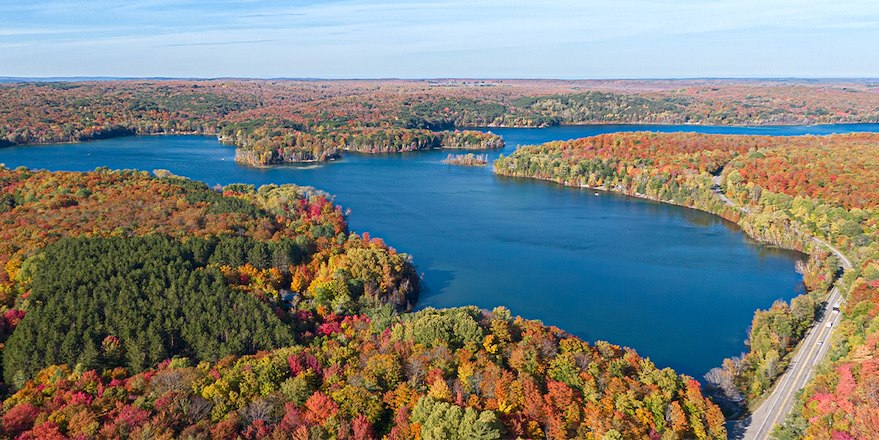 aerial view of leaves changing color around blue lake